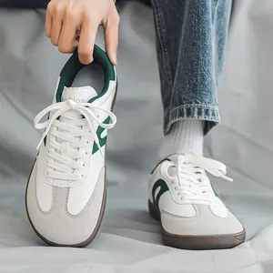 Primo piano di sneaker GAT bianche e verdi a punta larga con inserti in pelle e scamosciato.