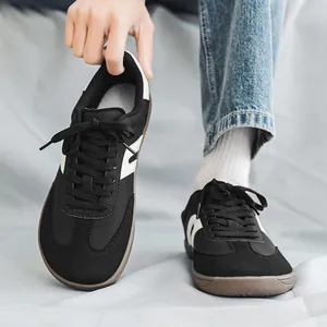 Dettaglio di sneaker a piedi nudi nere a punta larga con strisce bianche