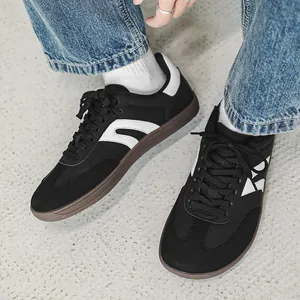 Dettaglio di sneaker minimaliste nere con punta larga e strisce laterali bianche classiche.