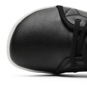 Macro detail of black leather barefoot shoe toe box with visible texture and laces