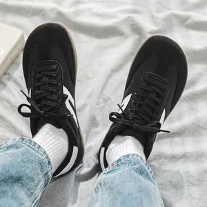 Dettaglio dall'alto di sneaker minimaliste nere GAT a punta larga indossate con jeans