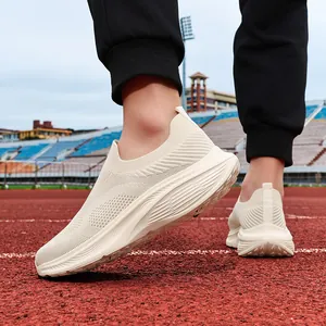 Close-up detail of men's beige breathable knit slip-on sneakers on a running track