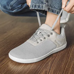 Gros plan d'une chaussure pieds nus gris clair à bout large lacée sur un sol en bois
