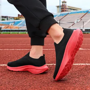 Breathable men's black fly-knit slip-on sports shoes with red soles on running track