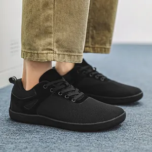 Vue détaillée de baskets minimalistes noires à bout large portées avec un pantalon kaki et tapis