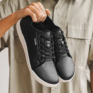 Detailed view of black faux leather wide-toe barefoot sneakers with durable white soles.