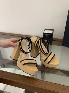 Vue détaillée des sandales à plateforme en paille beige avec brides noires à la cheville.