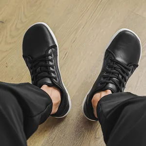 Top-down detailed view of black leather barefoot shoes with wide toe box on wooden floor
