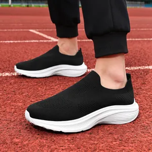 Close-up of men's black breathable mesh slip-on sneakers shown on a red running track.