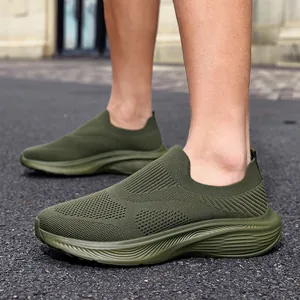 Close-up view of olive green fly-knit slip-on sneakers highlighting the breathable texture.