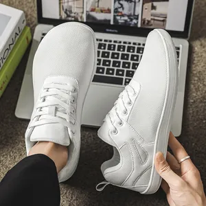 Vue détaillée de baskets pieds nus en maille blanche à bout large à côté d'un laptop