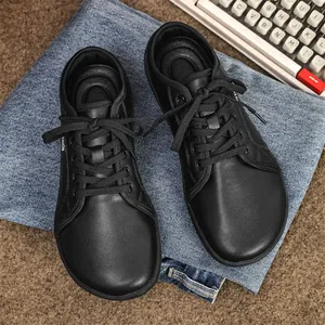 Top view of black wide-toe barefoot leather sneakers placed on denim background
