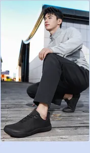 Detail shot of black wide toe men's hiking shoes worn by a model in outdoor setting