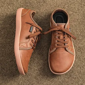 Detailed view of brown leather wide-toe barefoot sneakers on a textured brown carpet