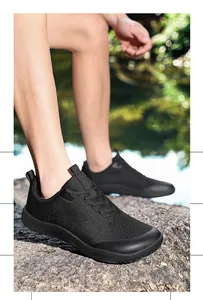 Black wide-toe barefoot hiking shoes for men shown in an outdoor rocky terrain setting