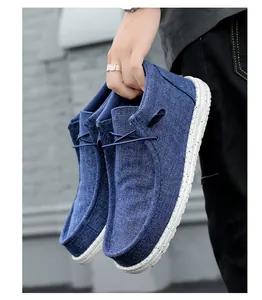 Pair of blue high-top canvas loafers held by hand, showing textured white soles