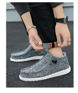 Close-up detail of gray canvas loafers on model with black denim pants