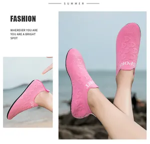 Dettaglio di scarpe da scoglio in maglia rosa traspirante indossate sui piedi al mare