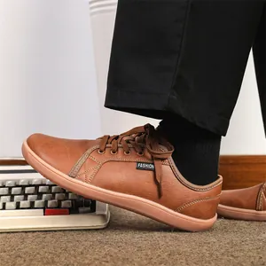 Side view of brown leather barefoot shoes with laces on a vintage typewriter