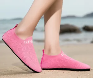 Primo piano di scarpe da acqua rosa traspiranti in maglia su una spiaggia soleggiata