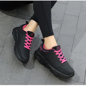 Dettaglio di sneakers da donna nere con lacci rosa vivace e suole in gomma strutturate