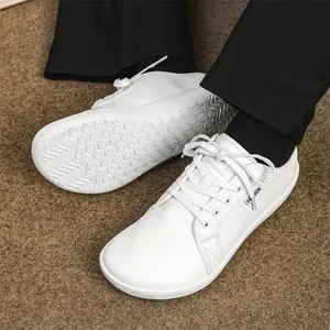 Detail view of white leather wide-toe barefoot shoes showing the anti-slip outsole