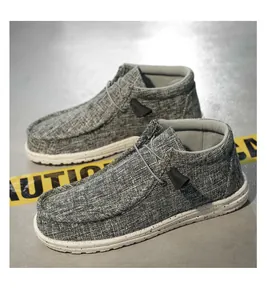 Detailed view of grey high-top canvas loafers on an industrial caution background