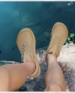 POV shot of tan wide-toe barefoot hiking shoes on a rocky outdoor setting