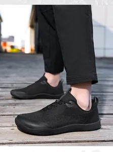 Side profile detail of black wide toe box barefoot hiking shoes on a wooden boardwalk