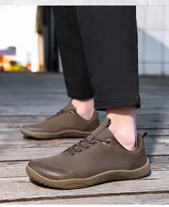 Detailed close-up of brown wide-toe barefoot hiking shoes worn on a wooden path