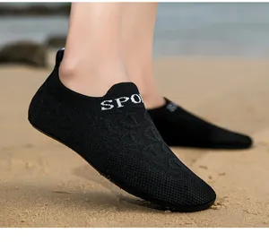 Dettaglio di scarpe da wading in maglia nera con scritta SPORT sulla sabbia della spiaggia.