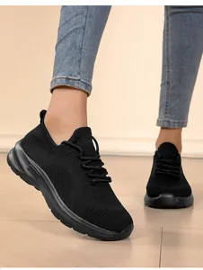 Detailed view of lightweight black fly-knit sneakers for women being worn with blue jeans