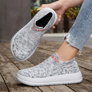 Close-up detail of breathable grey flyknit slip-on sneakers with white platform soles