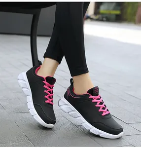 Primo piano di sneakers casual da donna in pelle nera con lacci rosa su una modella