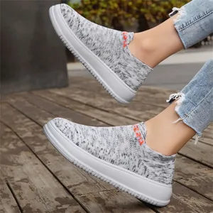 Close-up of breathable grey fly-knit slip-on sneakers on a wooden floor