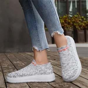 Lightweight and breathable casual grey flying weave slip-on sneakers worn on a wooden deck