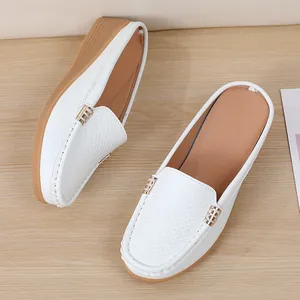 Gedetailleerde weergave van witte lederen loafers voor dames met geperforeerde textuur en goud.
