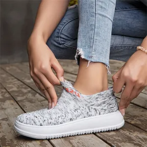 Close-up view of breathable grey fly-knit slip-on sneakers with thick white soles