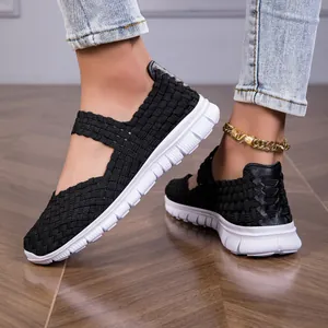 Close-up of black woven elastic strap sandals on female feet with white soles