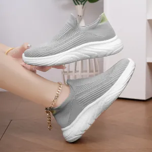 Detailed view of grey breathable knitted slip-on sneakers with white textured sole
