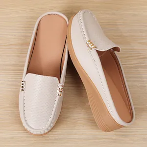 Detailweergave van de geperforeerde textuur en sleehakzool van beige slip-on loafers