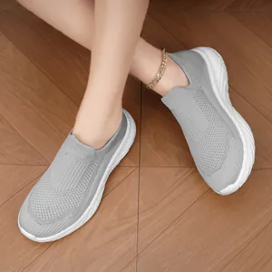 Detailed view of grey breathable knit slip-on sneakers for men on wooden floor