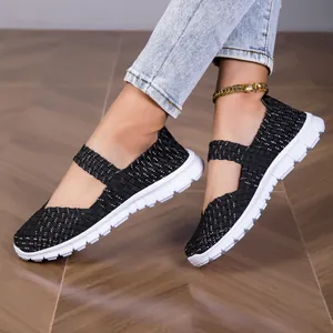 Close-up detail of black woven elastic strap sandals with flexible white flat soles