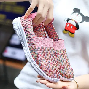 Detailed view of pink elastic woven women's casual slip-on shoes held by hand to show texture