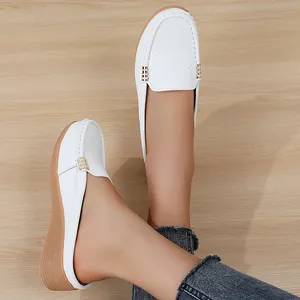 Close-up van witte geperforeerde loafers met gouden accenten en een sleehak
