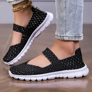 Detailed view of black woven elastic strap flat sandals with lightweight white sole