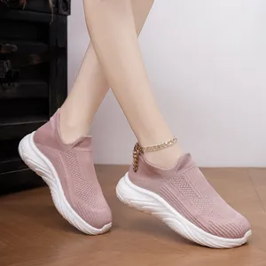 Detail of pink breathable slip-on knitted sneakers with chunky white sole on foot.