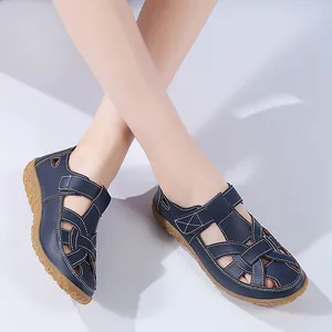 Dunkelblaue flache Leder-Sandalen mit Ausschnitten für Damen, präsentiert am Modell