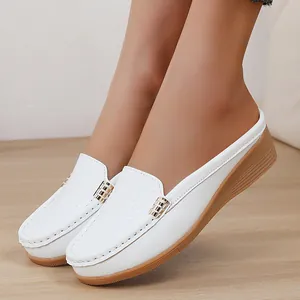 Detail van witte sleehakschoenen met getextureerd bovenwerk en een gouden gesp.