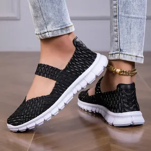 Detailed view of lightweight black woven elastic sandals with white flat sole on feet